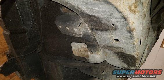 Underside of vehicle frame and wheel well with rust and black undercoating
