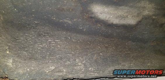 Underside of a vehicle showing textured undercoating or rustproofing.