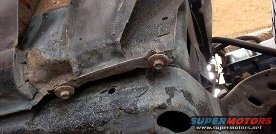 Close-up of rusted metal frame with bolts and bracket on a vintage vehicle.