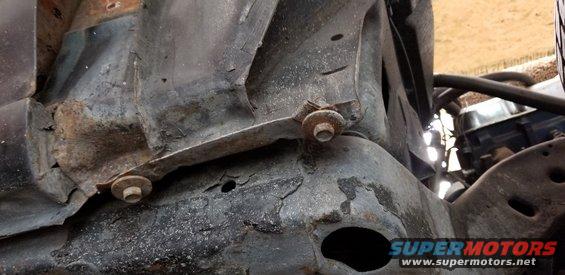 Close-up of rusted vehicle frame components with bolts.
