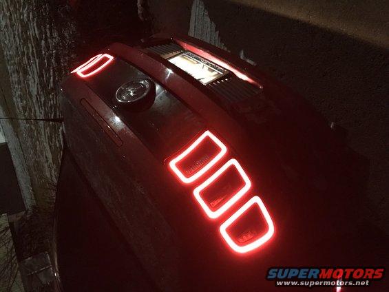 Red car trunk with illuminated rectangular accents and a central emblem