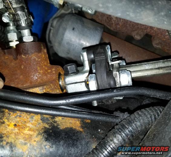 Close-up of rusty steering linkage components and black hoses