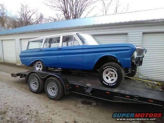Blue station wagon with a white roof on a trailer. It has custom wheels and raised suspension