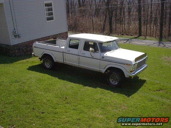 White 1977 Ford F-250 crew cab pickup truck parked on a grassy lawn next to a house