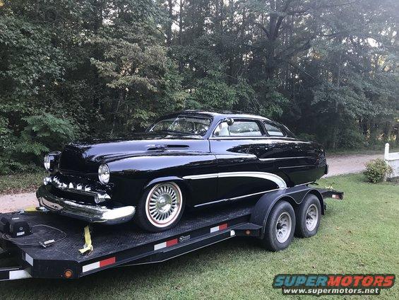 Black 1951 Mercury Sedan on a trailer, viewed from the front 3/4 angle, with chrome accents and whitewall tires