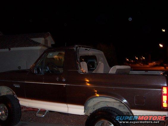 Brown and white 1992 Ford Bronco, side view, with removable top section, parked at night