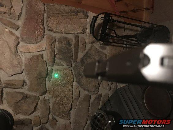 laser pointer beam on stone wall near fireplace tools