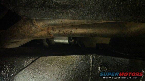 Underside view of vehicle frame and exhaust pipe with a Supermotors.net watermark