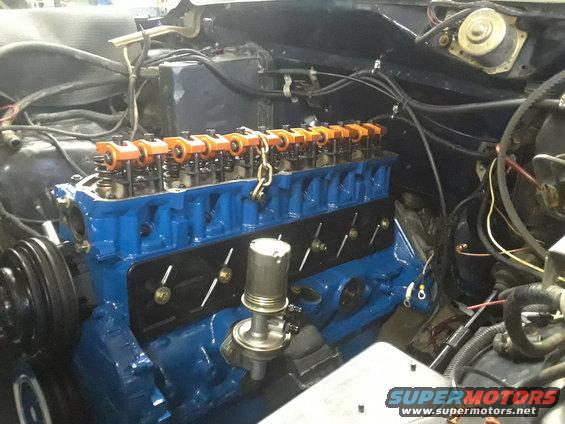 Blue engine block with orange valve covers and a fuel pump. Some wiring is visible