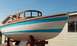 1991 Ford Bronco - A boat with a wooden cabin structure sits on a trailer in front of a house.