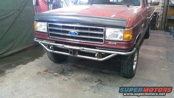 Red 1991 Ford F-150 with custom bumper and aftermarket wheels, front view