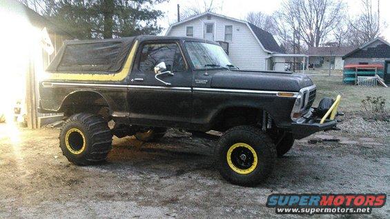 Black 1978 Ford Bronco with yellow trim, lifted with large off-road tires and yellow rims