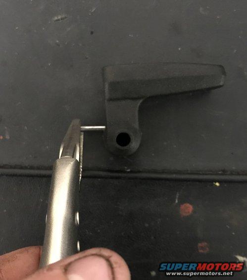 Black plastic lever with pin held by pliers