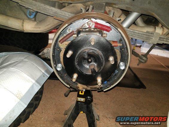 Rear drum brake assembly on jack stands, showing brake shoes, springs, and wheel cylinder