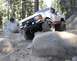 1984 Ford Bronco - A white and red Ford Bronco navigates a rocky trail in a wooded area.