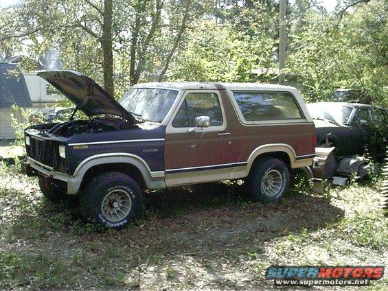 1985 Ford Bronco, 3q-front view, brown and tan with hood open. Another vehicle is partially visible behind it