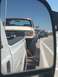 1984 Ford Bronco - A line of trucks, including a lifted Bronco, are seen on the road.