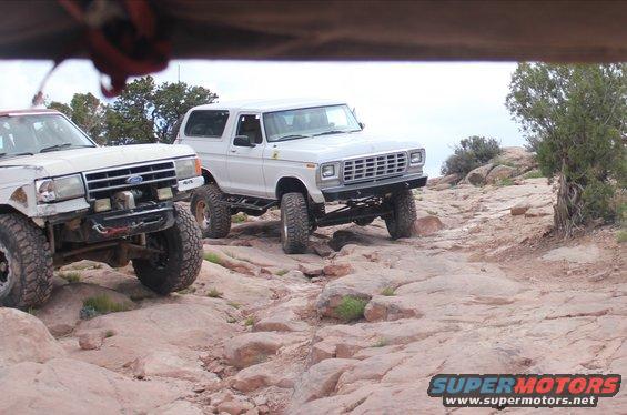 White Ford Bronco with lifted suspension on rocky trail. Grille indicates 1978 model year
