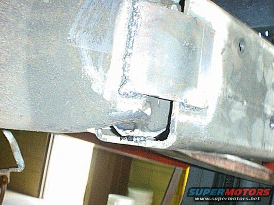 Close-up of a welded metal bracket on a vehicle frame, possibly part of a suspension or hitch