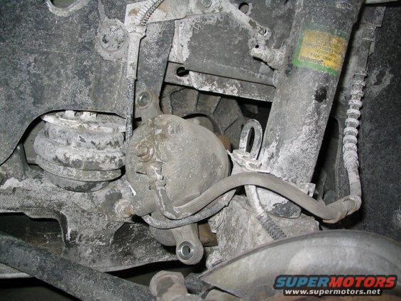 Rear brake caliper and suspension components covered in dust. A yellow Motorcraft sticker is visible on the shock absorber