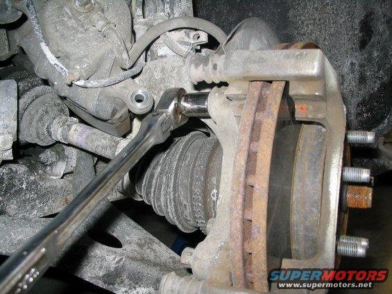 Brake caliper being removed with a socket wrench