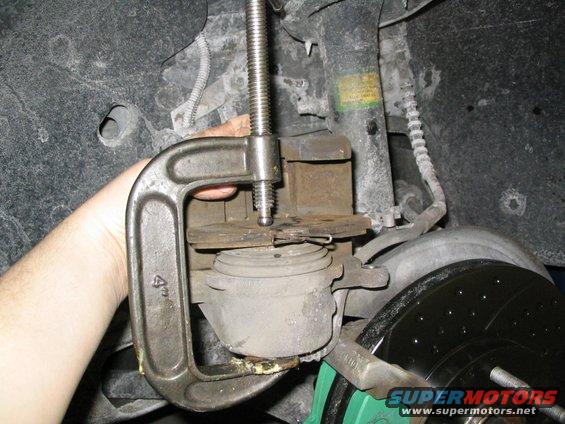 C-clamp compressing brake caliper over rotor. Green caliper bracket visible