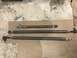 1984 Ford Bronco - Three adjustable steering linkage rods are displayed on a workbench, possibly workshop, floor.