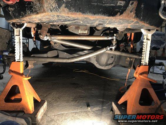 Undercarriage of a vehicle on jack stands, showing suspension and differential