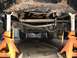 1984 Ford Bronco - Undercarriage of a vehicle supported by jack stands, with a focus on the steering and suspension components.