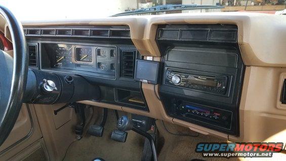 Dashboard of a tan 1980s Ford truck with a Pioneer stereo and aftermarket GPS