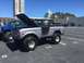 1979 Ford Bronco - A silver Ford Bronco is parked in a lot with its hood up, next to another vehicle.