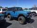 1979 Ford Bronco - A blue Ford Bronco is parked in a lot with other vehicles under a clear sky.