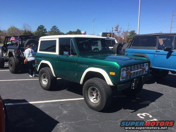 Green 1979 Ford Bronco with white top parked next to other vehicles