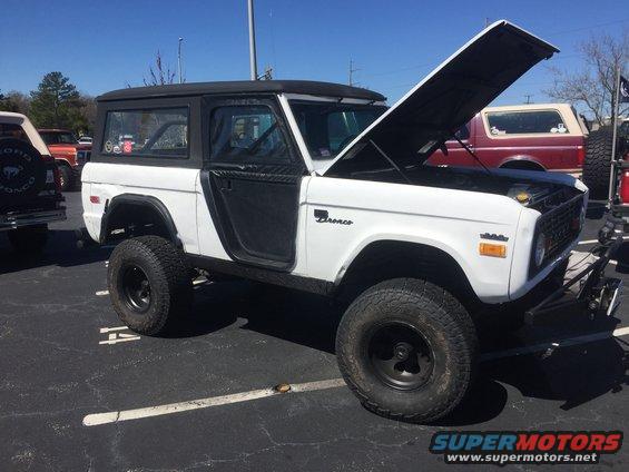 White Ford Bronco with hood open, parked in a lot next to another Bronco
