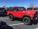 1979 Ford Bronco - A red 1979 Ford Bronco is parked in a lot next to another vehicle.
