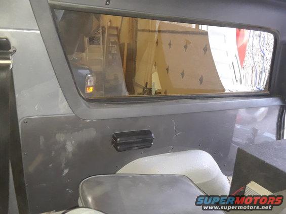 Interior paneling and window of a vehicle, showing a black grab handle