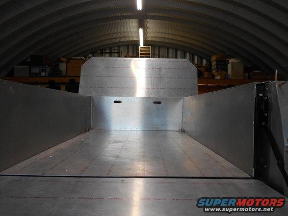 Empty aluminum truck bed interior, viewed from front. Metal walls and floor