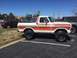 1979 Ford Bronco - This 1979 Ford Bronco features a distinctive orange and white stripe pattern and a removable soft top, parked in a lot.