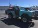 1979 Ford Bronco - A modified Ford Bronco is parked in a lot under a clear blue sky, with an American flag flying from a rear-mounted pole.