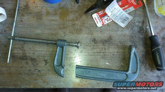 C-clamp, screwdriver, and packaging for drill bits on a workbench