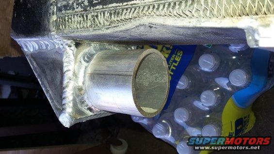 Welded metal pipe protruding from a radiator, with bottles of water in the background