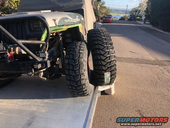 Jeep Wrangler front fender and large off-road tires on a tow truck ramp