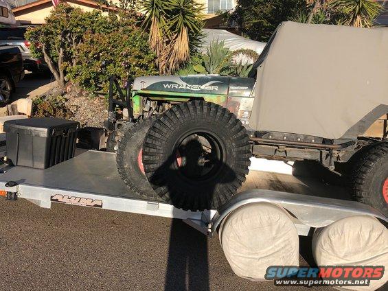 Green Jeep Wrangler with large tires on a trailer
