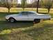 1960 Ford Starliner - A white 1960 Ford Starliner coupe sits on a grassy lawn, displaying its distinctive body lines and signs of age.