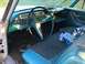 1960 Ford Starliner - The interior of a vintage car shows a turquoise dashboard, steering wheel, and patterned seats, with some papers on the passenger seat.