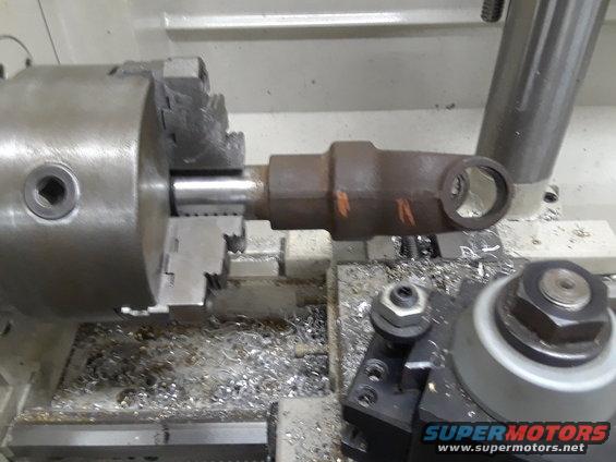 Driveshaft part being machined on a lathe, with metal shavings scattered