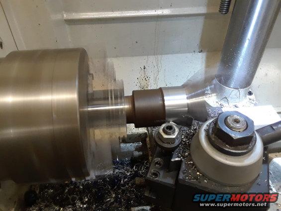 Metal part being machined on a lathe with shavings on the tool rest