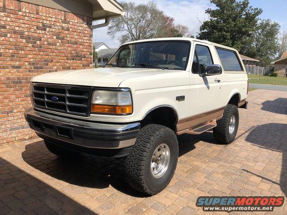 White 1995 Ford Bronco with brown trim parked on a brick driveway