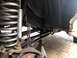1995 Ford Bronco - Underbody view of suspension parts, including a large coil spring and shock absorber, supported by jack stands.