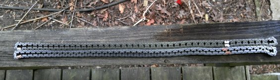 Two metal timing chains laid out on a wooden surface
